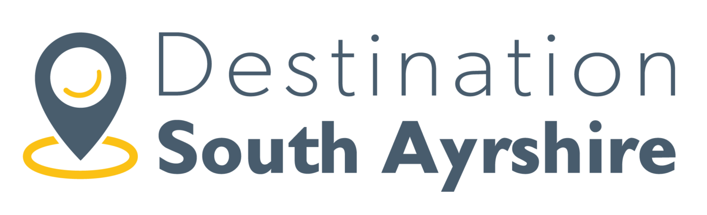 Destination South Ayrshire logo comprised of a dark grey wordmark accompanied by a map pin icon with a splash of yellow